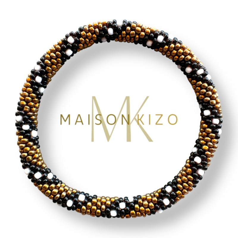 Bracelet jonc népalais de chez "MAISONKIZO" composé de perles dorées, noires et blanches. L'ensemble forme un motif élégant et artisanal.