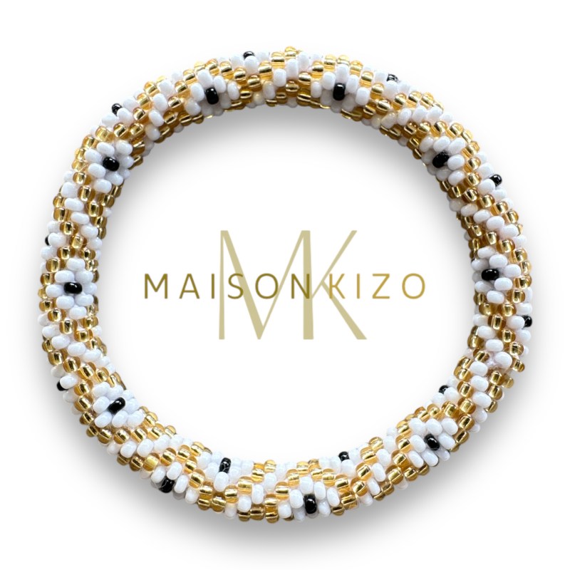 Bracelet jonc népalais de chez "MAISONKIZO" composé de perles dorées, blanches et bleues. L'ensemble forme un motif élégant et artisanal.