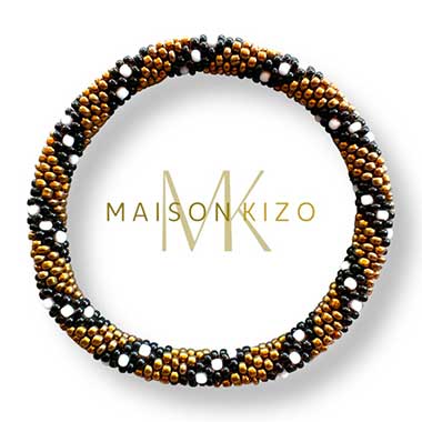 Bracelet jonc népalais de chez "MAISONKIZO" composé de perles dorées, noires et blanches. L'ensemble forme un motif élégant et artisanal.